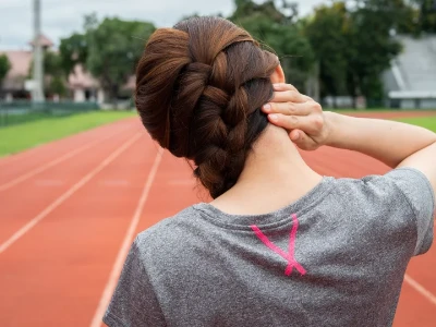 Femme ressentant des douleurs cervicales après avoir fait de l'exercice sur une piste de course à pied