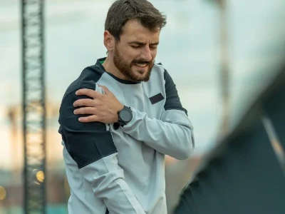 Homme ressentant une douleur due à une élongation musculaire de l'épaule droite après avoir couru
