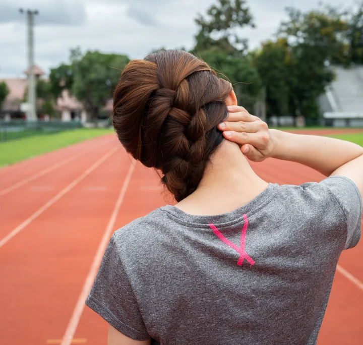 Femme ressentant des douleurs cervicales après avoir fait de l'exercice sur une piste de course à pied