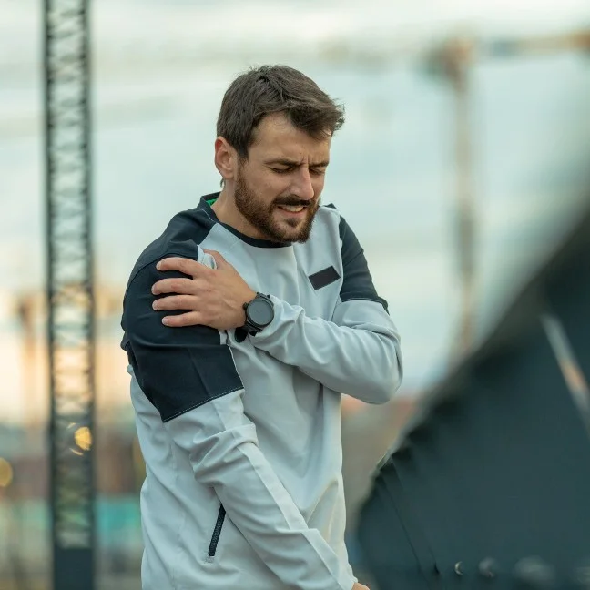 Homme ressentant une douleur due à une élongation musculaire de l'épaule droite après avoir couru