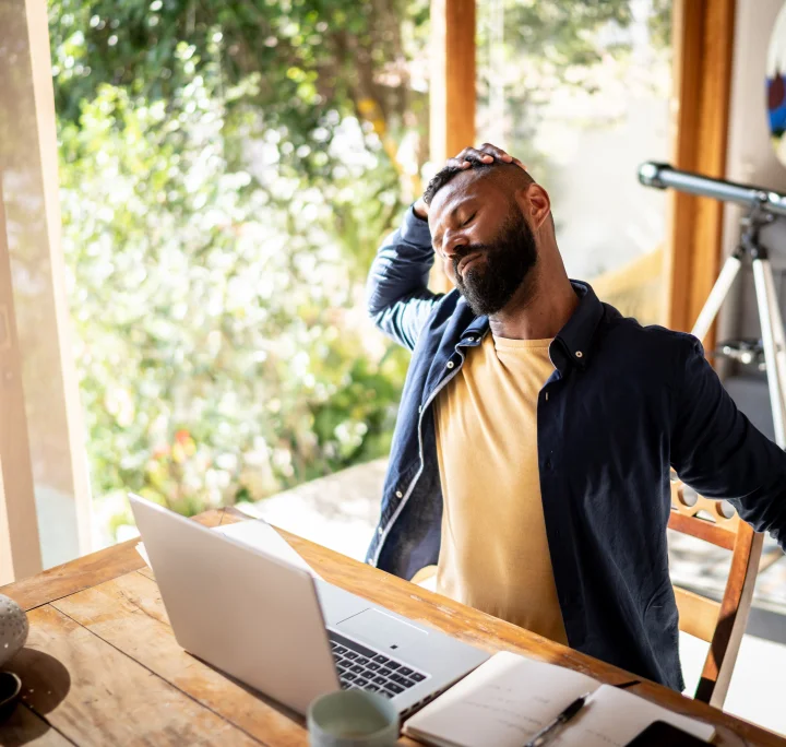 Homme travaillant dans son bureau à domicile et ressentant des douleurs corporelles dues à une position assise trop longue